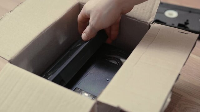 An old box with retro video cassettes on a floor.