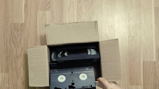 An old box with retro VHS tapes on a floor.