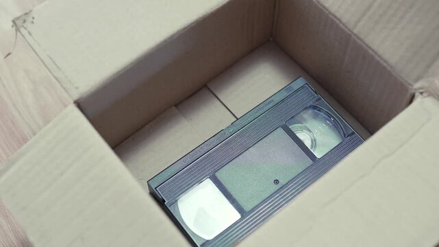An old box with retro VHS tapes on a floor.