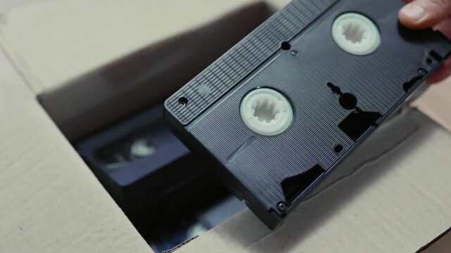 An old box with retro video cassettes on a floor.