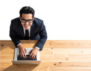 A confident businessman wearing glasses, smiling as he works on a laptop placed on a 