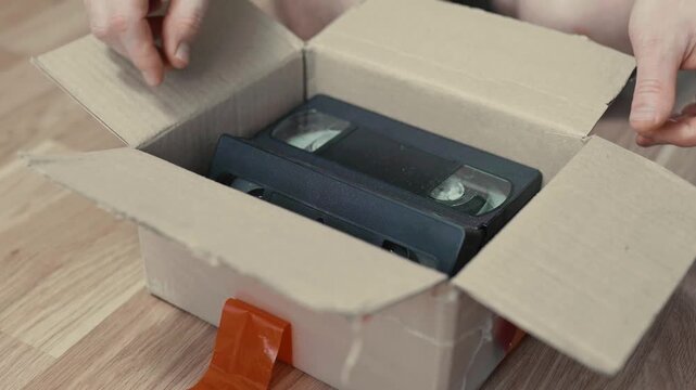 An old box with retro VHS tapes on a floor.