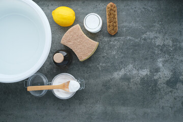 Cleaning supplies and natural ingredients organized on a gray surface ready for a spring cleaning session with lemon, vinegar, and baking soda. Natural cleaning products. Zero waste concept. top view.