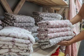 Woman holding a stack of soft, patterned towels in a store.