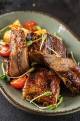 Grilled pork ribs with potato wedges and cherry tomatoes