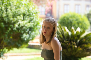 Portrait of a young, beautiful blonde woman wearing a green top, looking seriously and sadly at the...