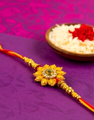 Rakhi bracelet, gold flower design,  on purple background