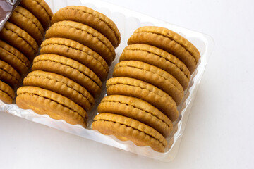 Several stacks of golden crackers in the transparent container, isolated on white background, showcasing their round shape and crispy texture. 