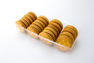 Several stacks of golden crackers in the transparent container, isolated on white background, showcasing their round shape and crispy texture. 
