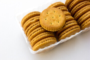 Several stacks of golden crackers in the transparent container, isolated on white background, showcasing their round shape and crispy texture. 