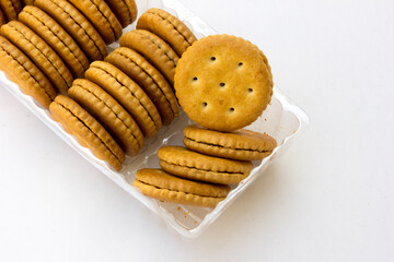 Several stacks of golden crackers in the transparent container, isolated on white background, showcasing their round shape and crispy texture. 