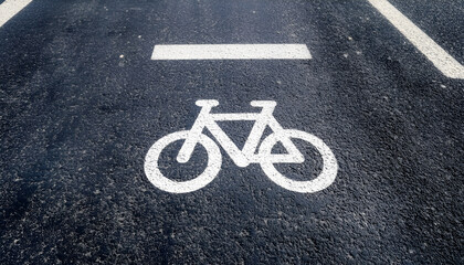 Obraz premium Overhead view of a bicycle lane marked with white lines and a bicycle symbol on gray asphalt. This clear urban street marking