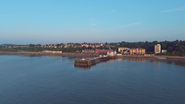 Aerial drone footage of Penarth seafront at sunrise overlooking the pier and residential areas. 