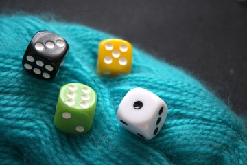 Brightly colored dice resting on a green yarn ball, close-up with copy space. Symbol of life’s thread, chance, fate, and free will.