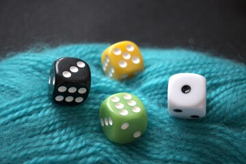 Brightly colored dice resting on a green yarn ball, close-up with copy space. Symbol of life’s thread, chance, fate, and free will.