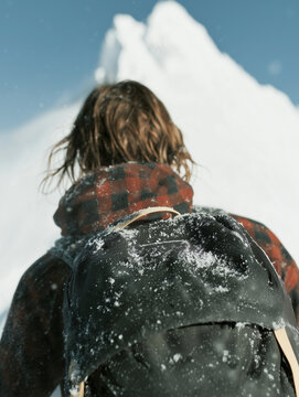 A woman hiking on a snowy mountain with a backpack. Outdoor sports and recreation in the winter mountains.
