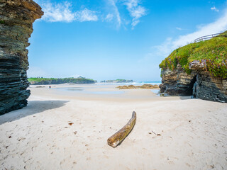 Playa des Catedrales in Galicia Spain sandstone rocks tidal pools sky cliffs wide shore under bright light clear blue sky peaceful calm natural wonder