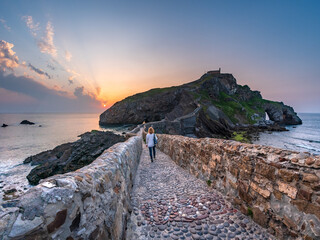 Ancient stone bridge leading to Gaztelugatxe islet at sunset Basque Country Spain symbol of journey solitude spirituality dramatic seascape inspiration