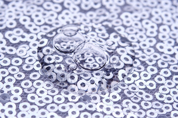 A drop of makeup on a background of silver sequins.