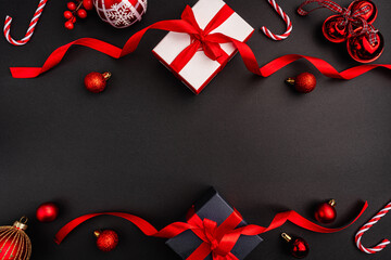 A festive flat lay featuring Christmas gift boxes with red bows, red baubles, candy canes, and...
