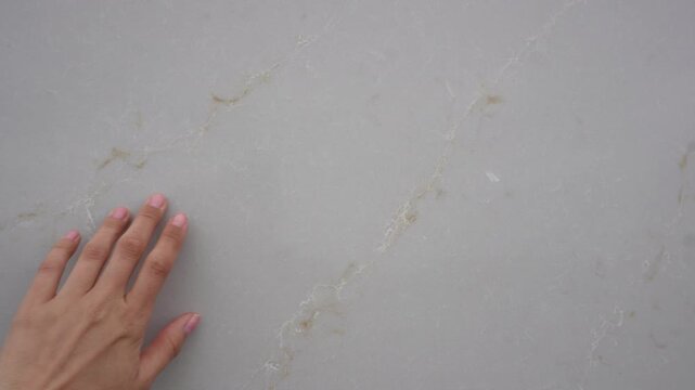 Women hand gently touching stone marble wall
