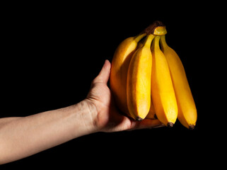 banana bunch in hand on black background