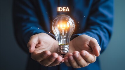 Two hands cupped together holding glowing holographic light bulb, futuristic IDEA concept symbolizing knowledge, creativity, innovation, and inspiration