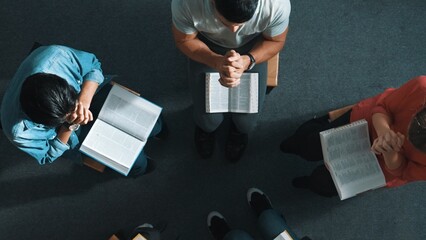 Top down view of prayers reading bible with cross on the laps while making folded hands. Aerial...