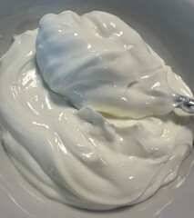 a white bowl of fresh creamy yogurt with a spoon