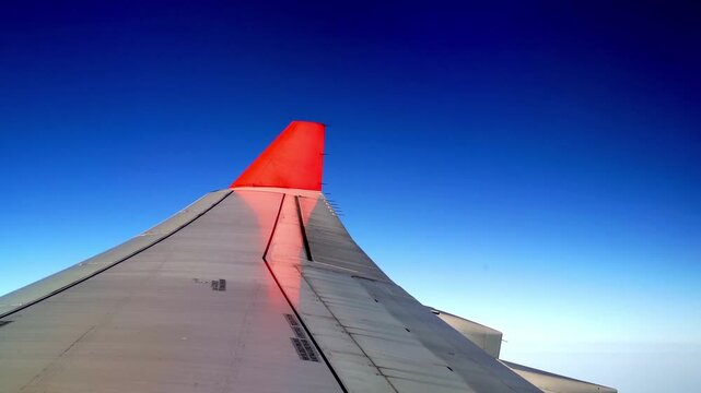 Airplane wing against blue sky background. View from the airplane elluminator