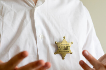 Man in White Shirt Displaying a Sheriff Badge
