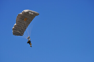 Uniformed soldier flying with a parachute