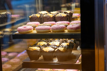 Pink Donuts, Muffins, and Other Sweets on Display in a Café Window
