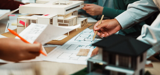 A dynamic architectural planning session shows a collaborative team working on models and drawings,...