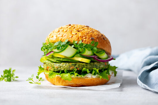 Healthy vegan burger with vegetables patty on a white parchment paper. Grey background. Close up.