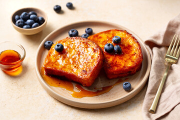 French toast with maple syrup and fresh blueberries. Beige background. Close up.