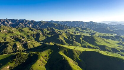 Lush green mountains and valleys under a clear blue sky