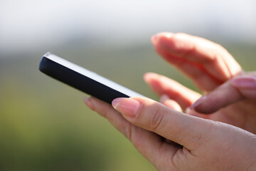 Smartphone in female hands, woman using mobile phone outdoor