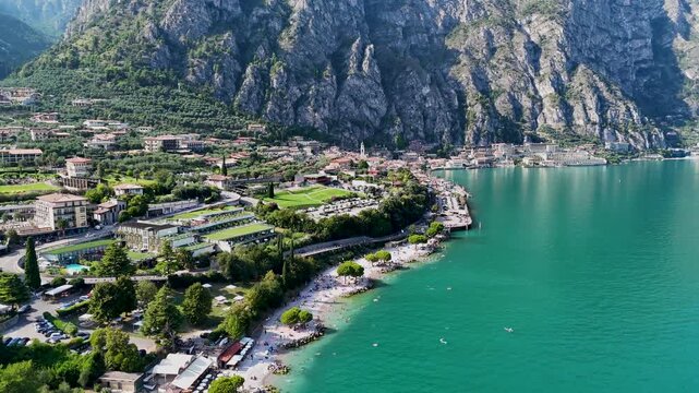 Limone sul Garda beach with people at a beach swimming and sunbathing. Aerial 4K video footage of panoramic lake Garda. Lombardy drone landscape