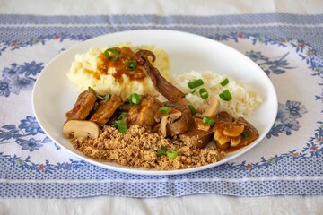 Traditional rustic Brazilian dish, beef tongue in Madeira sauce, mushrooms, rice, farofa and mashed potatoes