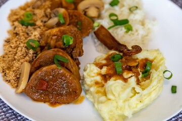 Traditional rustic Brazilian dish, beef tongue in Madeira sauce, mushrooms, rice, farofa and mashed potatoes