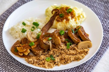 Traditional rustic Brazilian dish, beef tongue in Madeira sauce, mushrooms, rice, farofa and mashed potatoes
