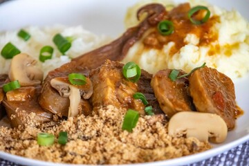 Traditional rustic Brazilian dish, beef tongue in Madeira sauce, mushrooms, rice, farofa and mashed potatoes