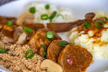 Traditional rustic Brazilian dish, beef tongue in Madeira sauce, mushrooms, rice, farofa and mashed potatoes