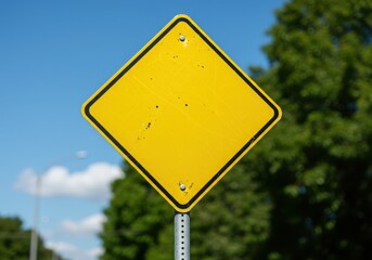 Blank yellow diamond warning sign against a blue sky