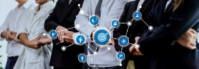 A diverse business team stands together in a modern office, connected by digital target symbols...