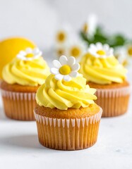 Three yellow cupcakes with white flower toppers