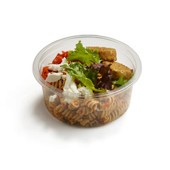 Fusilli pasta salad with tofu feta pesto and fresh green leaves in clear container