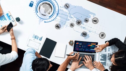 A modern business meeting scene featuring a collaborative team analyzing data on laptops, with digital visualizations overlaying a world map, highlighting teamwork and technology. Raster