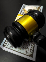 A judges gavel rests on a stack of 100 dollars bills.